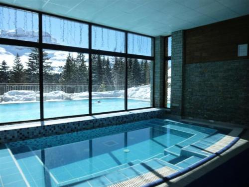 a large swimming pool in a room with a large window at Résidence Les Terrasses D'eos - Appartement confortable · Accès direct aux pistes · Piscine · Spa · WIFI gratuit et illimité MAE-6164 in Magland