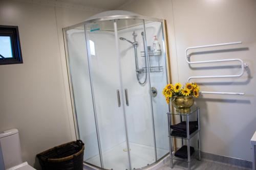 een douchecabine in een badkamer met een vaas met bloemen bij Alpine Views Farm Stay in Lake Coleridge