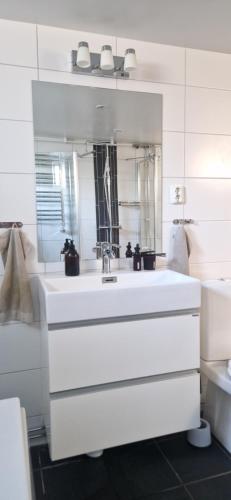 a white bathroom with a sink and a mirror at Calm Condo in villa area near nature in Vendelsö
