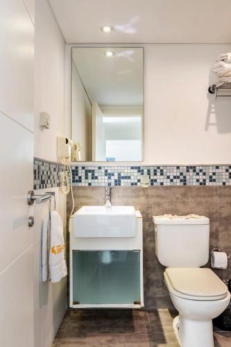 a bathroom with a sink and a toilet and a mirror at Arenas del Mar Apartments in Punta del Este
