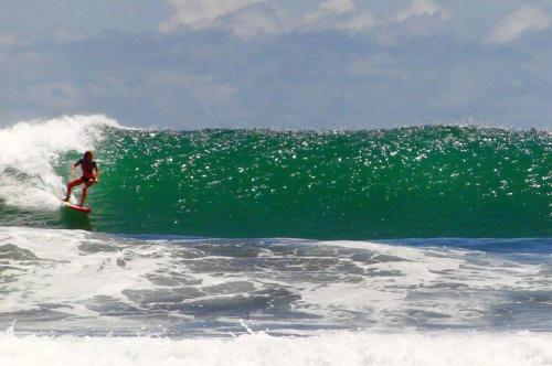 a person riding a wave on a surfboard in the ocean at Casa Azul with Private Pool - Tropical Oasis - WiFi-AC-Bikes-Surfboards- Walk to point in Pavones