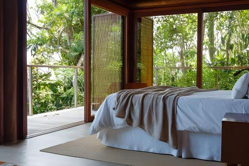 ein Schlafzimmer mit einem Bett und einem großen Fenster in der Unterkunft Villa Toucan in Itacaré