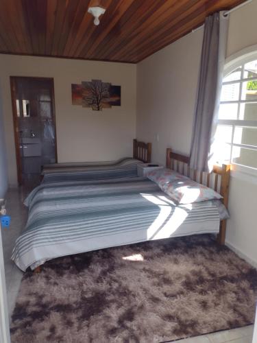 a large bed in a bedroom with a window at Casa do Trem Suítes in Campos do Jordão