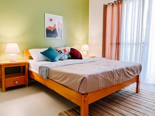 a bedroom with a bed with two lamps and a window at Hooga Home in Cebu City