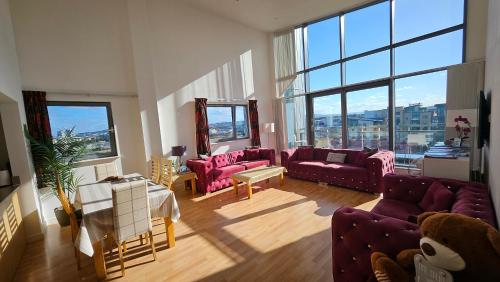 a living room with purple couches and large windows at Penthouse Ocean View Luxury Penthouse in Edinburgh