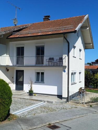 a white house with a balcony at Ferienwohnung Meyer in Neukirchen vorm Wald