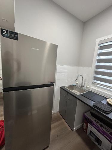 a kitchen with a stainless steel refrigerator and a sink at 1-bedroom private suite, 20 minutes from the airport, with a kitchen in Edmonton