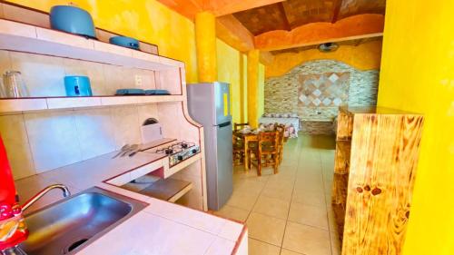 a kitchen with a refrigerator and a dining room with a table at Bungalows El Rincon de La Riviera in Rincon de Guayabitos