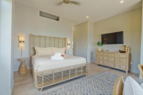 a bedroom with a bed and a dresser and a television at NEW 3 Story Waterfront 4Bedroom Villa with Amazing Sunset Mountain Views in Maya Beach