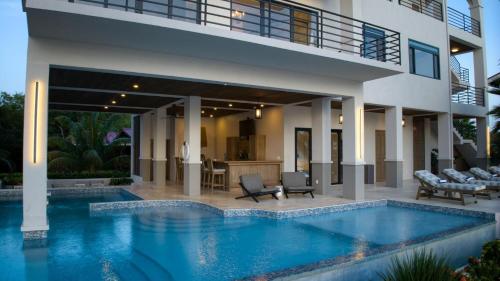 a house with a swimming pool in front of a house at NEW 3 Story Waterfront 4Bedroom Villa with Amazing Sunset Mountain Views in Maya Beach