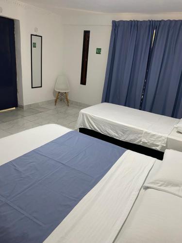 two beds in a room with blue curtains at Habitación independiente cerca al aeropuerto 1 in Cartagena de Indias