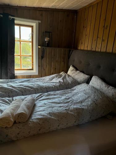a bedroom with a bed with two pillows and a window at Cabin in Silisjávri in Skillemo