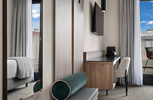 a hotel room with a bed and a desk and a television at Leonardo Hotel Vienna City West in Vienna