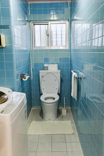 a blue tiled bathroom with a toilet and a window at Velvet House in Murokawa