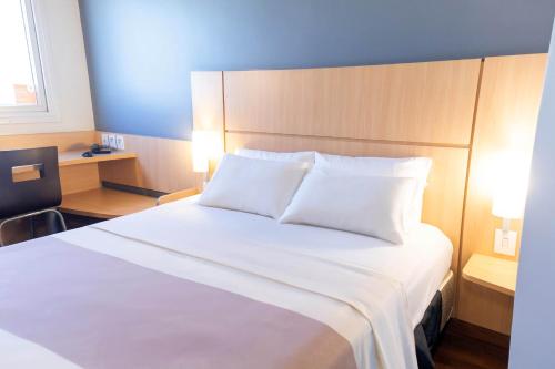 a bedroom with a large bed with white sheets at ibis Contagem Ceasa in Contagem