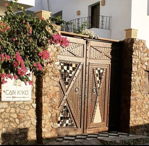 a wooden gate with flowers on a stone wall at Villa Can Kiko in Dahab
