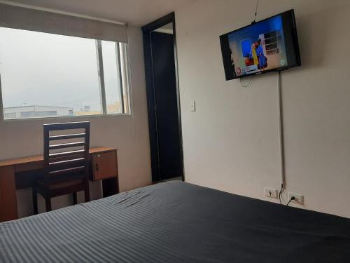 a bedroom with a bed and a television on the wall at Hotel Roma Bogota , Corferias , Cerca Embajada Americana , Universidad Nacional , G 12 ,Movistar Arena Agora Habitaciones y Apartaestudios muy bien ubicado a 30 minutos del Aeropuerto in Bogotá
