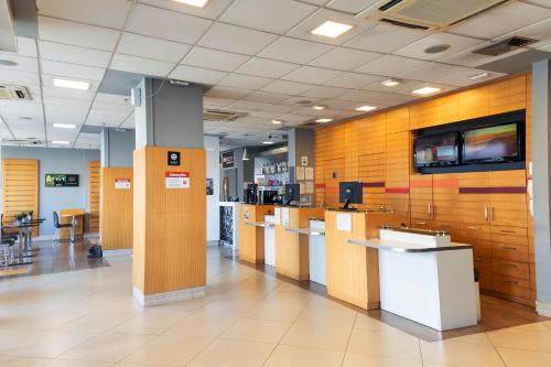a lobby of a hospital with tables and a tv on the wall at ibis Contagem Ceasa in Contagem