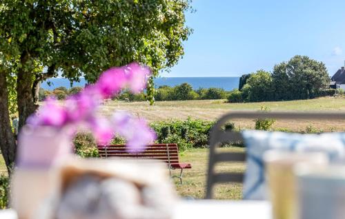 a park bench with pink flowers in the foreground at Nice Apartment In Nexø With Wifi in Neksø