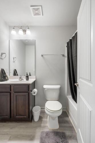 a white bathroom with a toilet and a sink at Elegant 3BR Retreat King Bed Near Cary & NC State in Raleigh