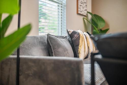 a couch with pillows in a living room with a window at Elegant 3BR Retreat King Bed Near Cary & NC State in Raleigh