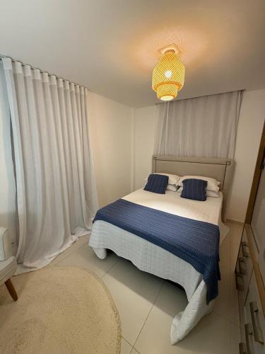 a bedroom with a bed with blue sheets and a chandelier at A pérola de Costa Azul in Rio das Ostras