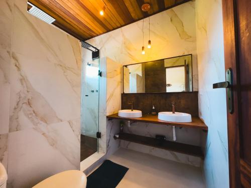 a bathroom with two sinks and a mirror at Hakuna Studios Barra do Sahy in Barra do Sahy
