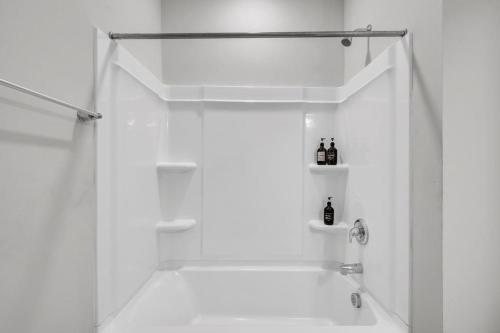 a white bathroom with a shower with bottles on shelves at Luxe King 4 BR Townhouse Mins to Dwtn Durham in Durham