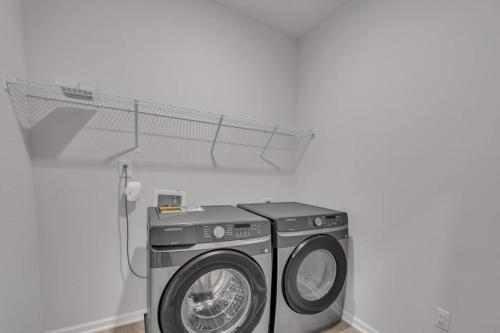 a washing machine in a room with a white wall at Luxe King 4 BR Townhouse Mins to Dwtn Durham in Durham
