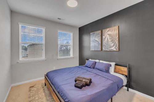 a bedroom with a large purple bed with two windows at Luxe King 4 BR Townhouse Mins to Dwtn Durham in Durham