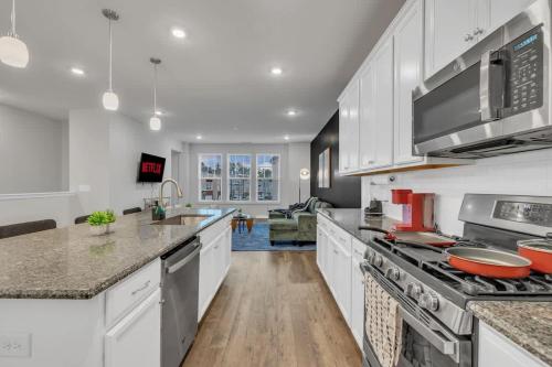 a kitchen with white cabinets and a stove top oven at Luxe King 4 BR Townhouse Mins to Dwtn Durham in Durham