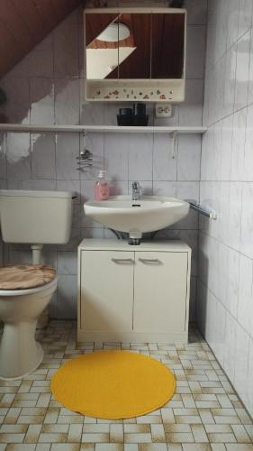 a bathroom with a sink and a toilet and a yellow rug at Ferienwohnung Bergblick in Trittenheim