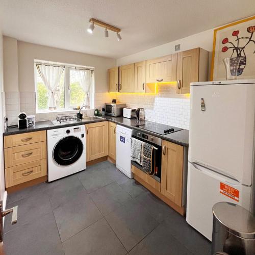a kitchen with a white refrigerator and a dishwasher at 2-Bed Apartment Near ExCeL - Free Parking & WiFi - Ideal for Families, Business & Leisure in London