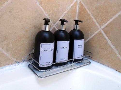 two black bottles sitting on a shelf in a bathroom at The olive stay at Edwardian unit F7 in Port Edward