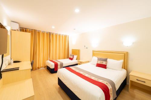 a hotel room with two beds and a television at Auckland Newmarket Motel in Auckland