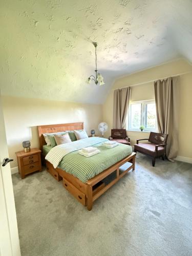 ein Schlafzimmer mit einem großen Bett und einem Stuhl in der Unterkunft Grange Cottage in Belmont