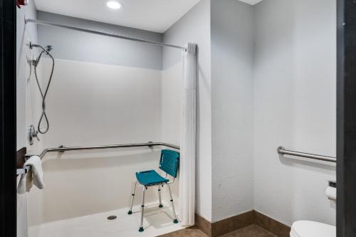 a bathroom with a blue chair in the shower at Baymont by Wyndham La Crosse/Onalaska in Onalaska