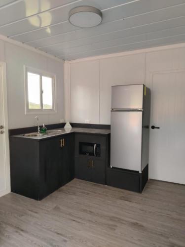a kitchen with black cabinets and a refrigerator at EcOsaLodge in Puerto Jiménez