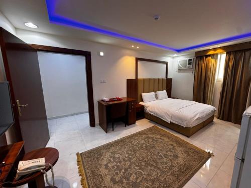 Un dormitorio con una cama, un escritorio y un televisor. en شقق ظل النخيل للشقق المخدومة, en Hotat bani tamim