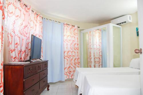 a bedroom with two beds and a tv and curtains at 2BR Villa Ocean Views Beach 5mins to Airport in Boscobel