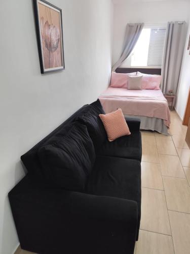 a black couch in a room with a bed at Studio Cyar 32 - Conforto e Praticidade in Taubaté