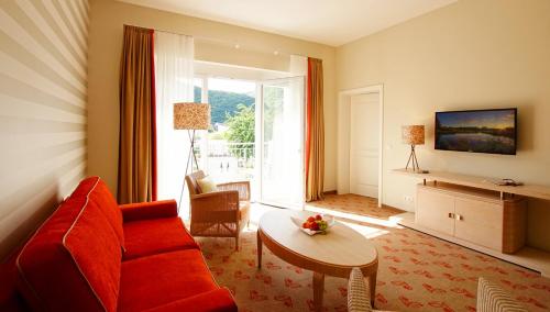 a living room with a red couch and a table at Landhotel Sanct Peter in Bad Neuenahr-Ahrweiler