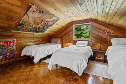two beds in a room with wooden walls at Jocko River Retreat - A Nature Lovers Dream in Arlee