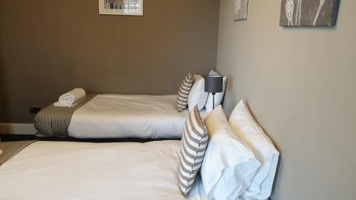 two beds with white sheets and pillows in a room at The Grapes Pub in Southampton