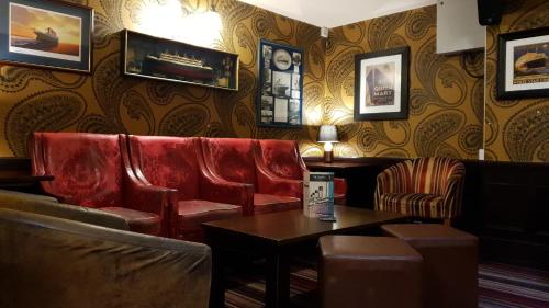 a bar with red leather chairs and a table at The Grapes Pub in Southampton