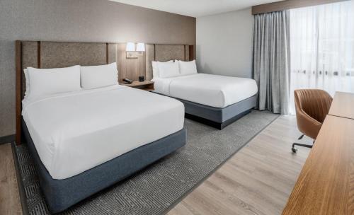 a hotel room with two beds and a desk at Holiday Inn Dublin - Pleasanton by IHG in Dublin