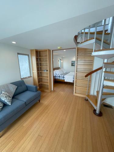 a living room with a blue couch and a spiral staircase at Dragan's Cove in Oxnard
