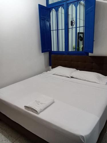 a white bed with a blue window in a room at Hotel casa Narvaez in Girardot