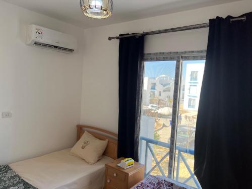 a bedroom with a bed and a large window at Mountain View Resort Chalet in Ras El Hekma in Ras Elhekma