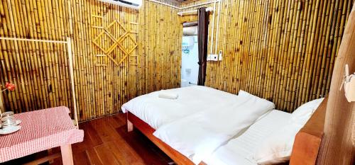 a small room with a bed and a table at SAKURA House - Vườn Đào in Mộc Châu